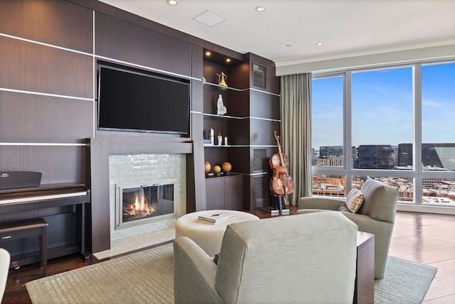 living room with a glass covered fireplace, wood finished floors, and recessed lighting