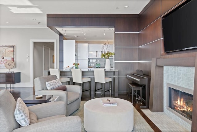 living room with ornamental molding, a tiled fireplace, baseboards, and wood finished floors