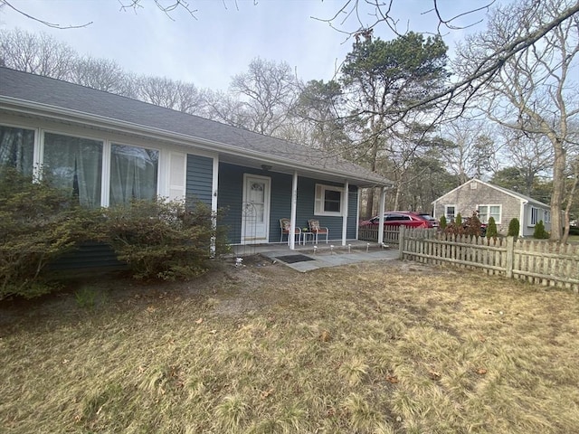 exterior space with a front lawn, fence, a porch, and roof with shingles