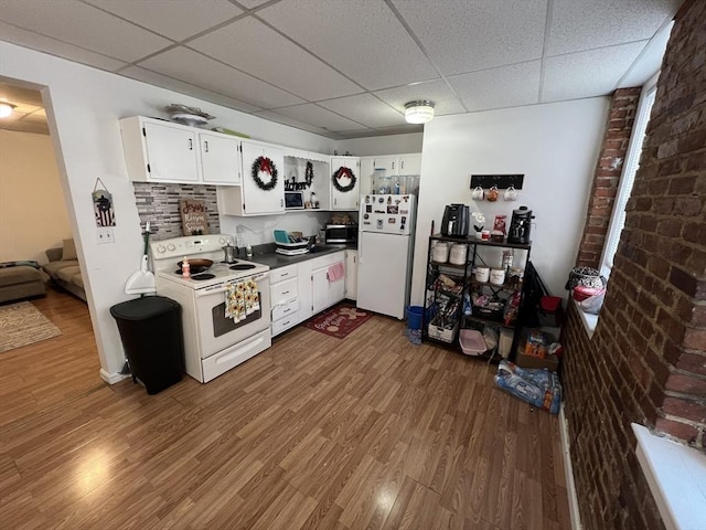 kitchen with white appliances, a paneled ceiling, dark hardwood / wood-style floors, and white cabinets