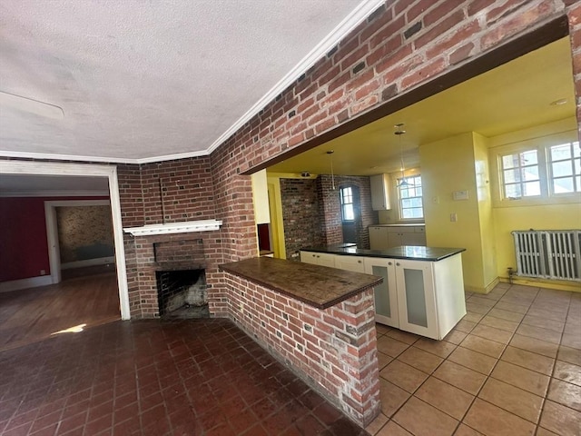 91-93 Mulberry St, Springfield, MA 01105 - kitchen featuring a textured ceiling, crown molding, dark countertops, a fireplace, and a peninsula