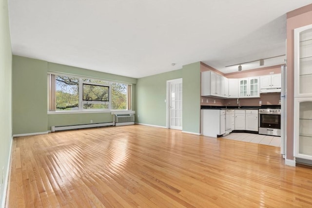 unfurnished living room featuring a baseboard radiator, light wood-style flooring, and baseboards