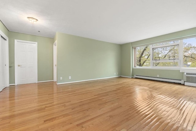 unfurnished living room featuring light wood-style flooring, baseboards, and a baseboard heating unit