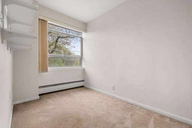 carpeted empty room featuring baseboards and a baseboard radiator