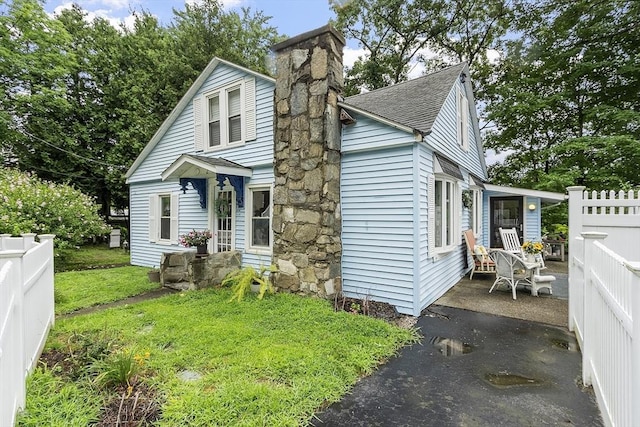 view of front of house featuring a shingled roof and a chimney