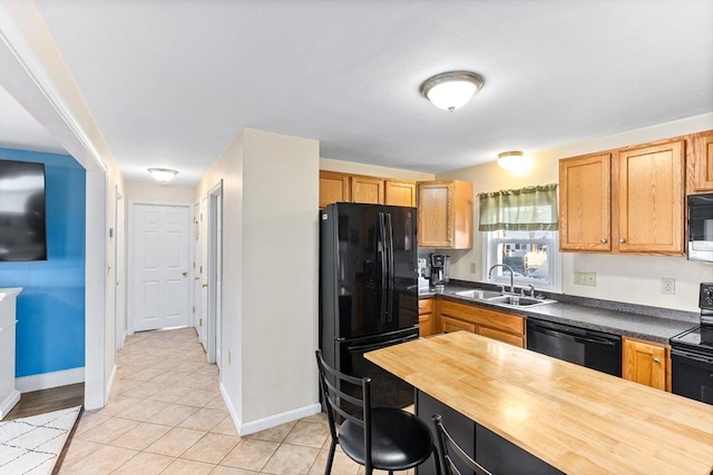 kitchen featuring sink, light tile patterned floors, wooden counters, and black appliances