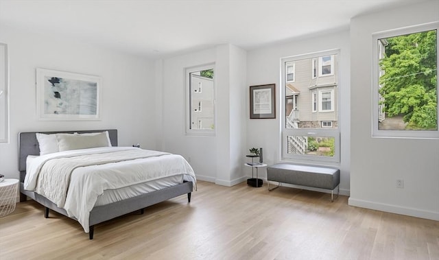 bedroom with light wood-style floors, multiple windows, and baseboards