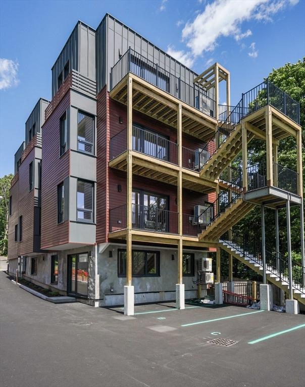 view of building exterior with stairs and uncovered parking