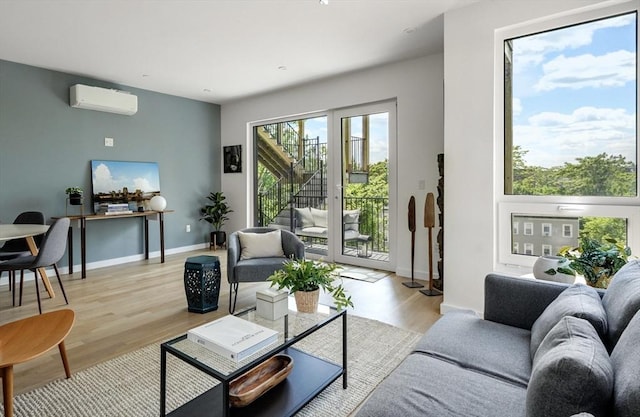 living area with light wood finished floors, a wall mounted AC, and baseboards