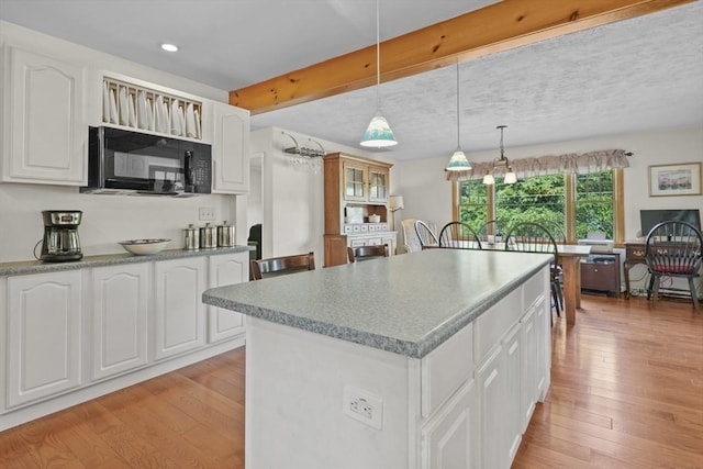 132 Biscayne St, Leominster, MA 01453 - kitchen with black microwave, a kitchen island, white cabinetry, light wood-style floors, and recessed lighting