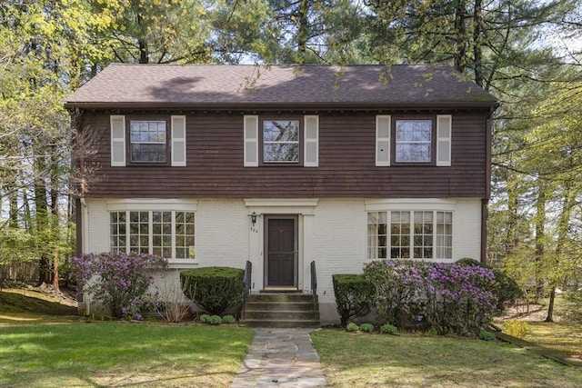 view of front of home featuring entry steps, a front yard, and brick siding