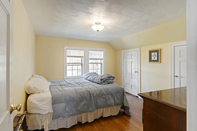bedroom with dark wood-style flooring and vaulted ceiling