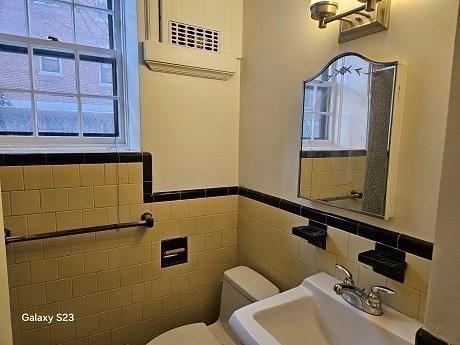 bathroom featuring tile walls, sink, and toilet