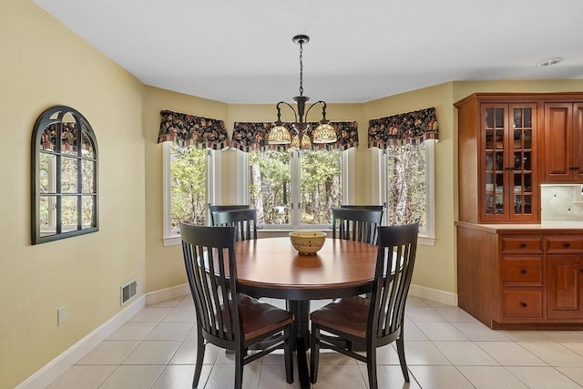 dining space with light tile patterned flooring, a notable chandelier, visible vents, and baseboards
