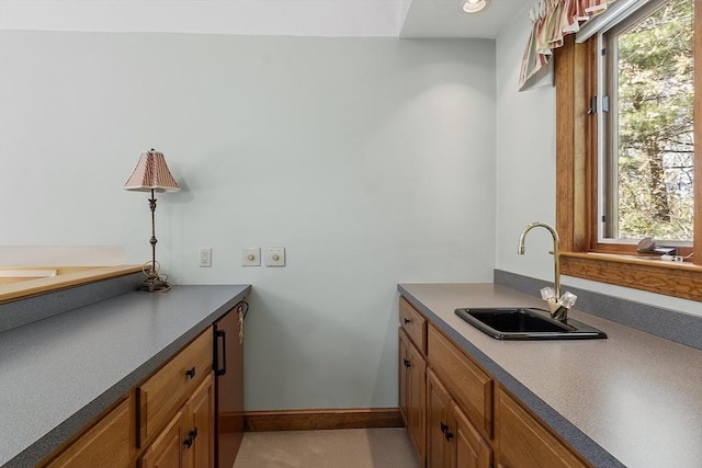 clothes washing area featuring baseboards and a sink