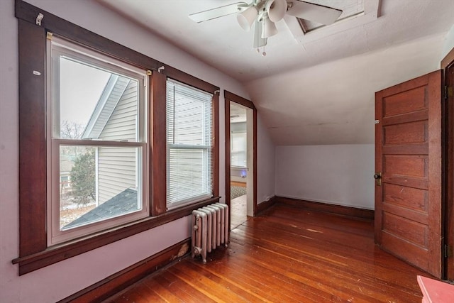 additional living space featuring dark hardwood / wood-style floors, lofted ceiling, radiator heating unit, and ceiling fan