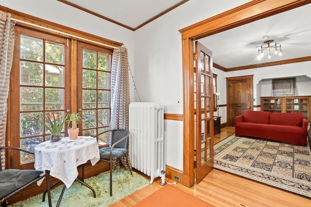 sitting room with wood-type flooring, ornamental molding, and radiator heating unit