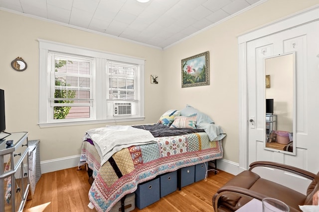 bedroom with light wood-type flooring, cooling unit, and ornamental molding