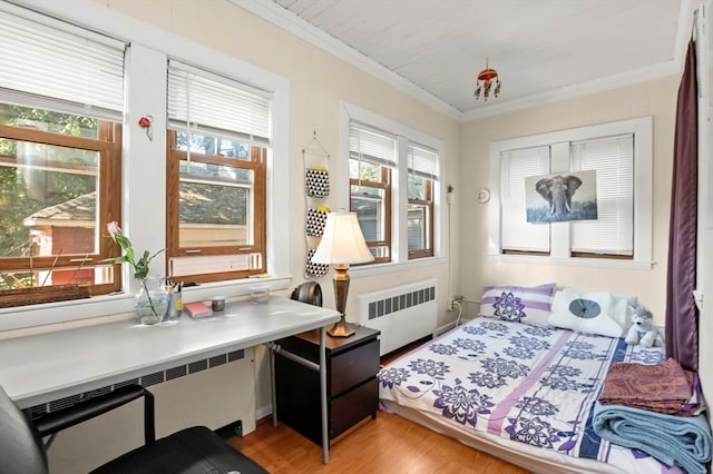 bedroom with ornamental molding, radiator, and light hardwood / wood-style floors