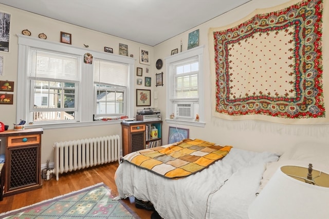 bedroom with cooling unit, hardwood / wood-style floors, and radiator heating unit