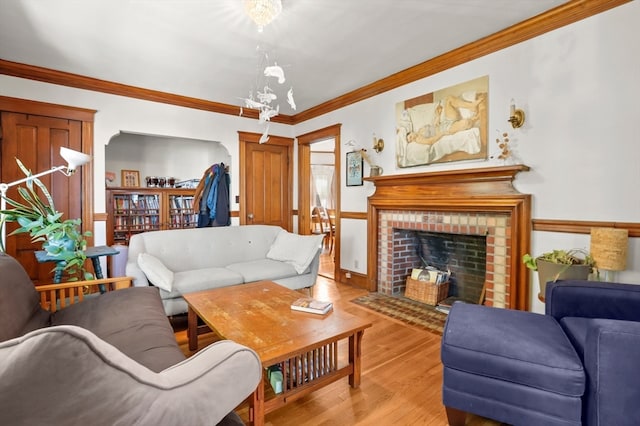 living room featuring a notable chandelier, light hardwood / wood-style floors, a fireplace, and crown molding