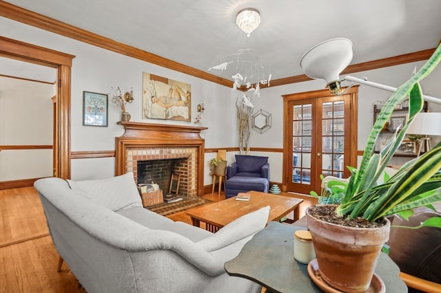 living room featuring hardwood / wood-style flooring, ornamental molding, and a brick fireplace