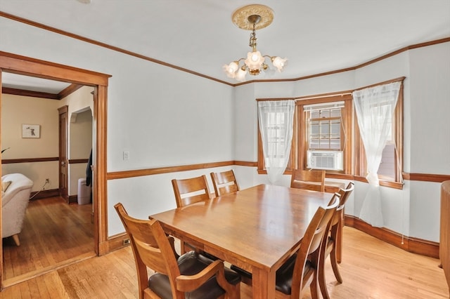 dining space with light wood-type flooring, cooling unit, ornamental molding, and a notable chandelier