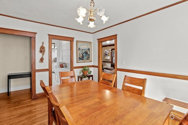 dining space featuring ornamental molding, light hardwood / wood-style flooring, and a notable chandelier