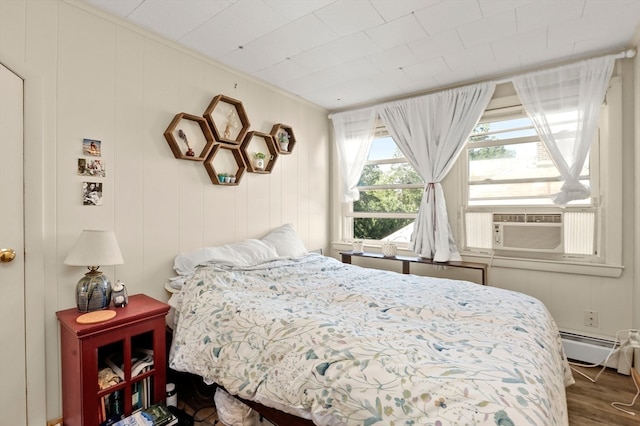 bedroom with cooling unit, baseboard heating, dark hardwood / wood-style floors, and ornamental molding