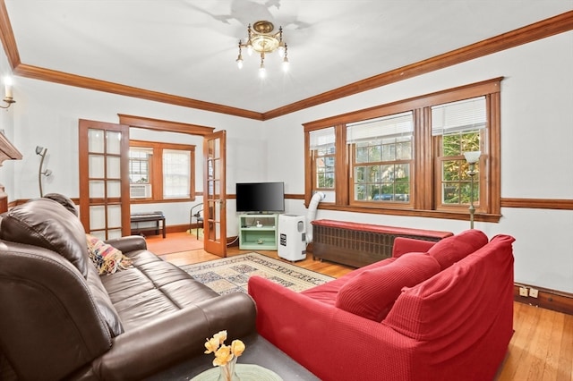 living room featuring light wood-type flooring, ornamental molding, radiator, and french doors