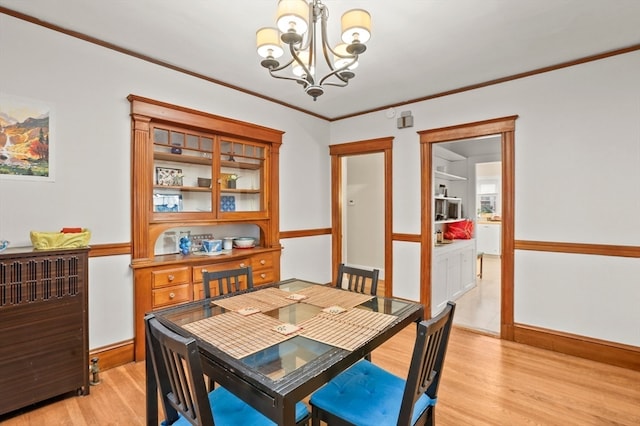 dining room with ornamental molding, light hardwood / wood-style flooring, and a notable chandelier