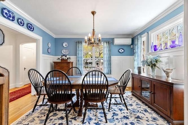 dining room featuring a decorative wall, a chandelier, a wall unit AC, and light wood-type flooring