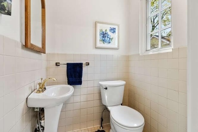bathroom featuring toilet, tile walls, and a wainscoted wall