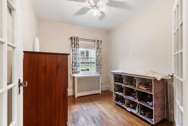interior space featuring wood finished floors, baseboards, ceiling fan, and radiator heating unit