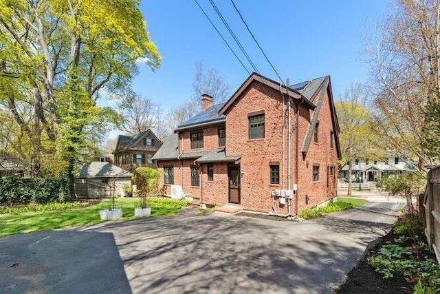 rear view of property with fence, a chimney, and brick siding
