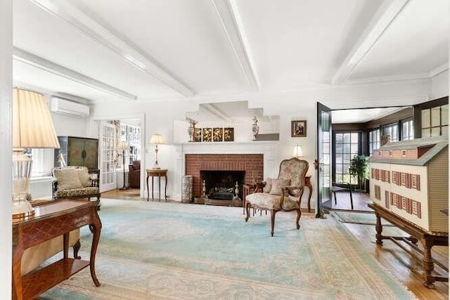 living area featuring a brick fireplace, an AC wall unit, and beam ceiling