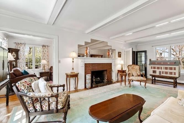 living room featuring a fireplace, beamed ceiling, a healthy amount of sunlight, and wood finished floors