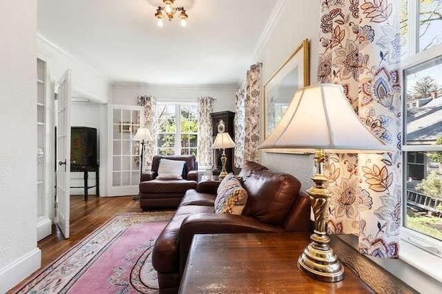 living area with baseboards, ornamental molding, and wood finished floors