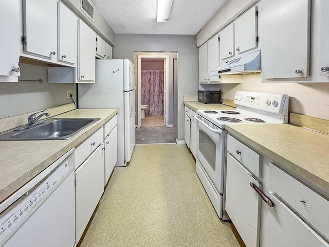 kitchen with white appliances, light countertops, white cabinetry, under cabinet range hood, and a sink