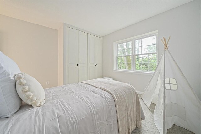 carpeted bedroom with a closet and baseboards