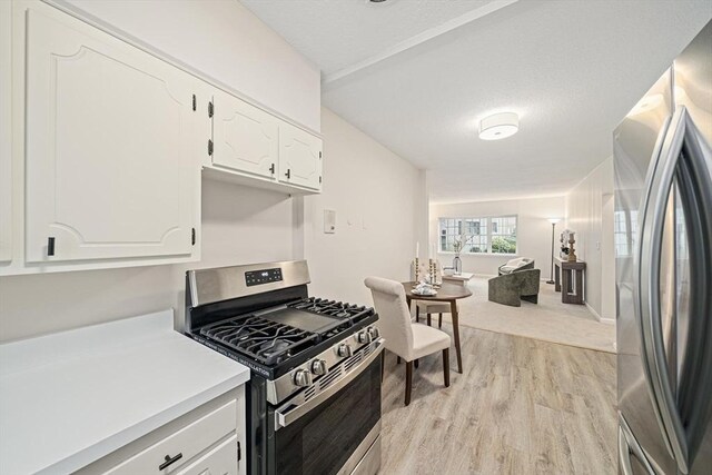 kitchen featuring appliances with stainless steel finishes, light wood finished floors, white cabinets, light countertops, and open floor plan