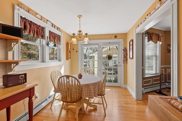 dining room featuring a notable chandelier, light wood-style floors, baseboard heating, and a healthy amount of sunlight