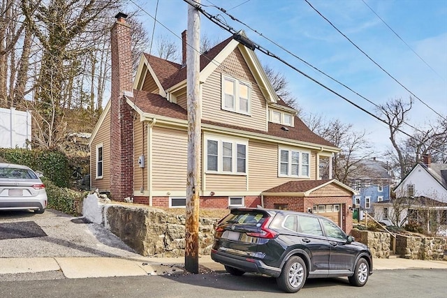 view of front facade with a shingled roof and a chimney