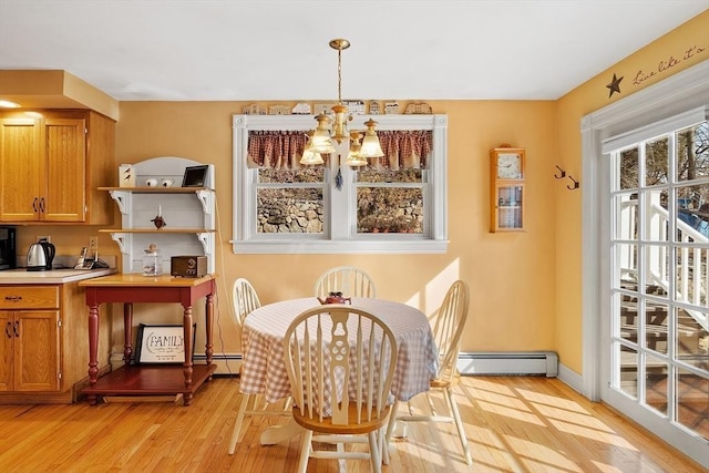 dining room with an inviting chandelier, light wood finished floors, baseboards, and baseboard heating