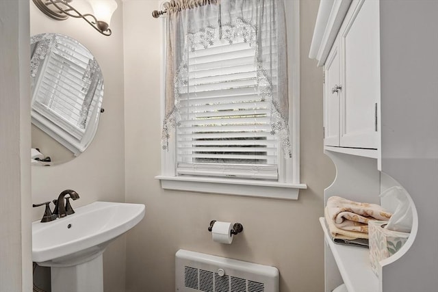 bathroom featuring plenty of natural light, radiator heating unit, and a sink