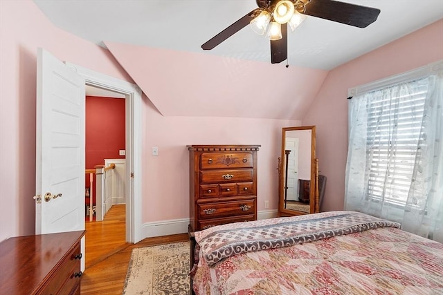 bedroom featuring lofted ceiling, wood finished floors, baseboards, and ceiling fan