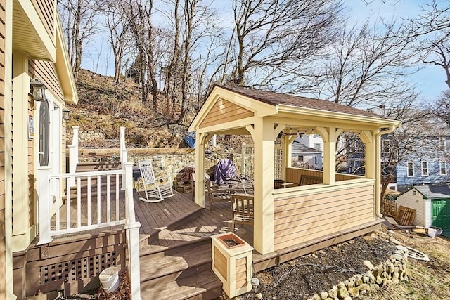 wooden deck featuring a gazebo and an outbuilding