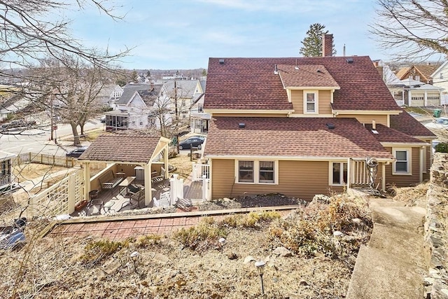 back of property with a gate, fence, a chimney, and a shingled roof