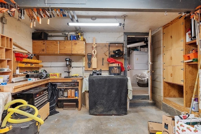 interior space featuring a workshop area, concrete block wall, and stacked washer and dryer