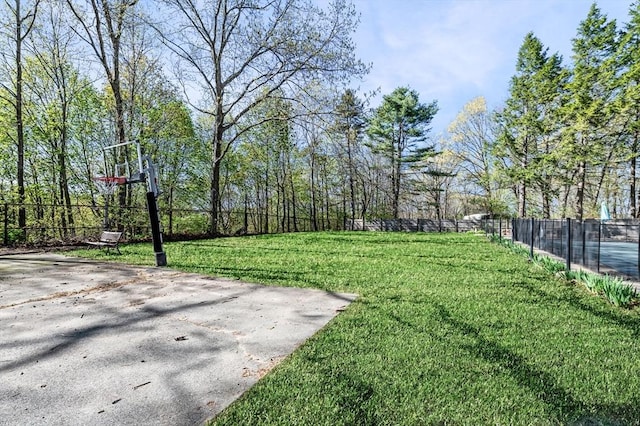 view of yard with community basketball court and fence